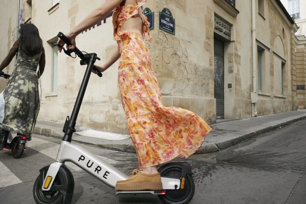 Fahrerin mit Pure Advance Plus E-Scooter auf einer Stadtstraße