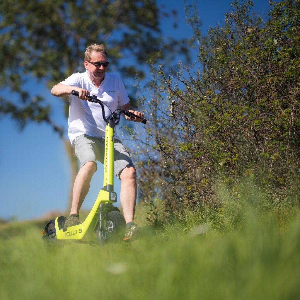 Fahrer mit STREETBOOSTER Castor E-Scooter auf einem Weg im Grünen