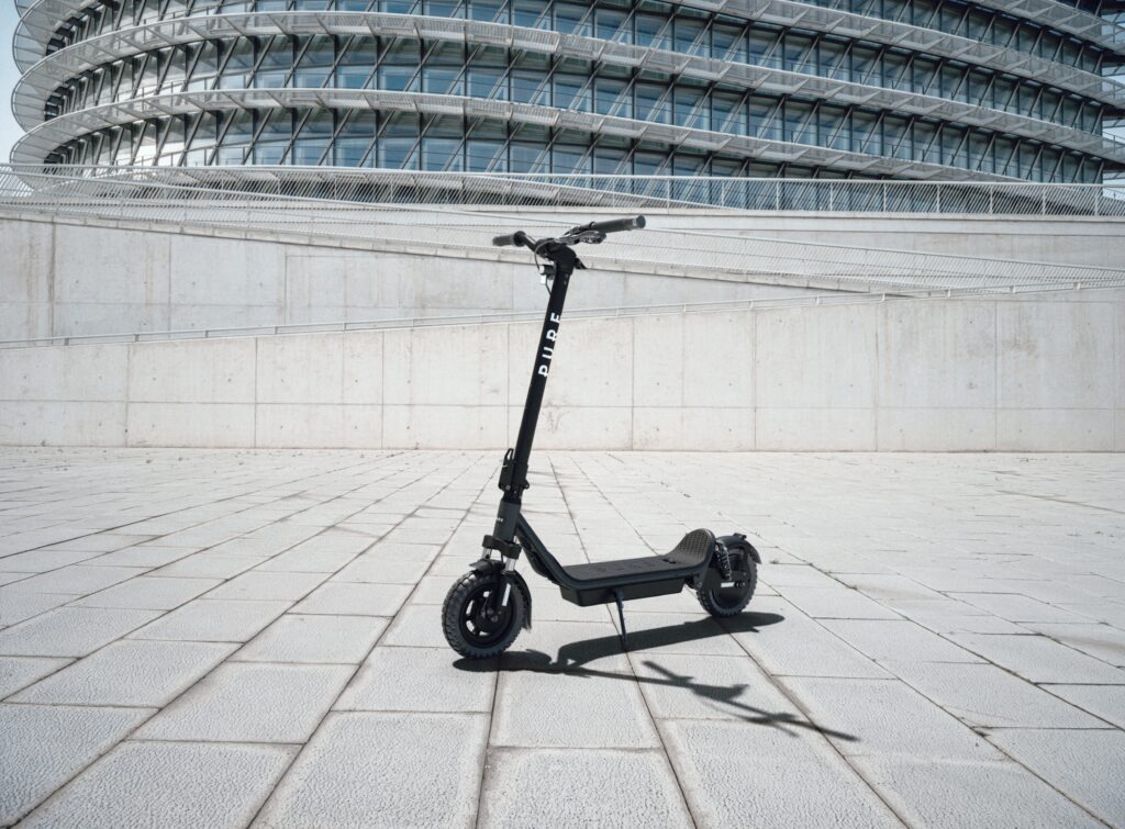 Pure Air6 E-Scooter vor moderner Architektur als breites Titelmotiv