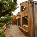 Haus Wipfelbett von Minimalus mit Holzfassade und Terrasse an einer alten Eiche